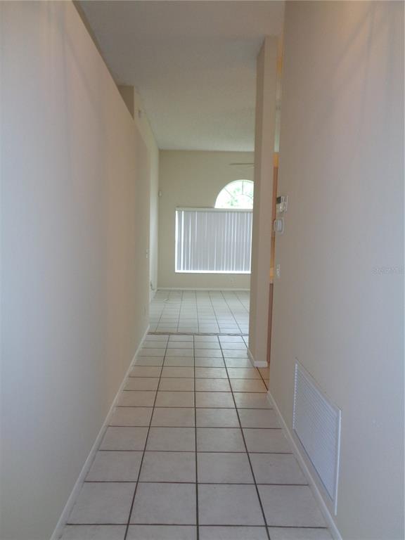 A tiled hallway leads to an open living area with a large window and blinds — 2125 RIVER PARK BOULEVARD, ORLANDO, FL