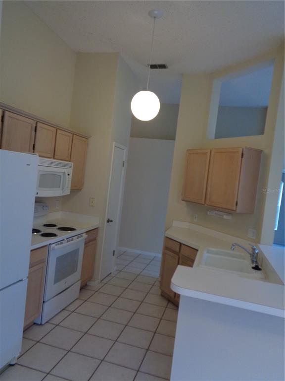 A kitchen with light wood cabinets, white appliances, tile flooring, and a high vaulted ceiling — 2125 RIVER PARK BOULEVARD, ORLANDO, FL