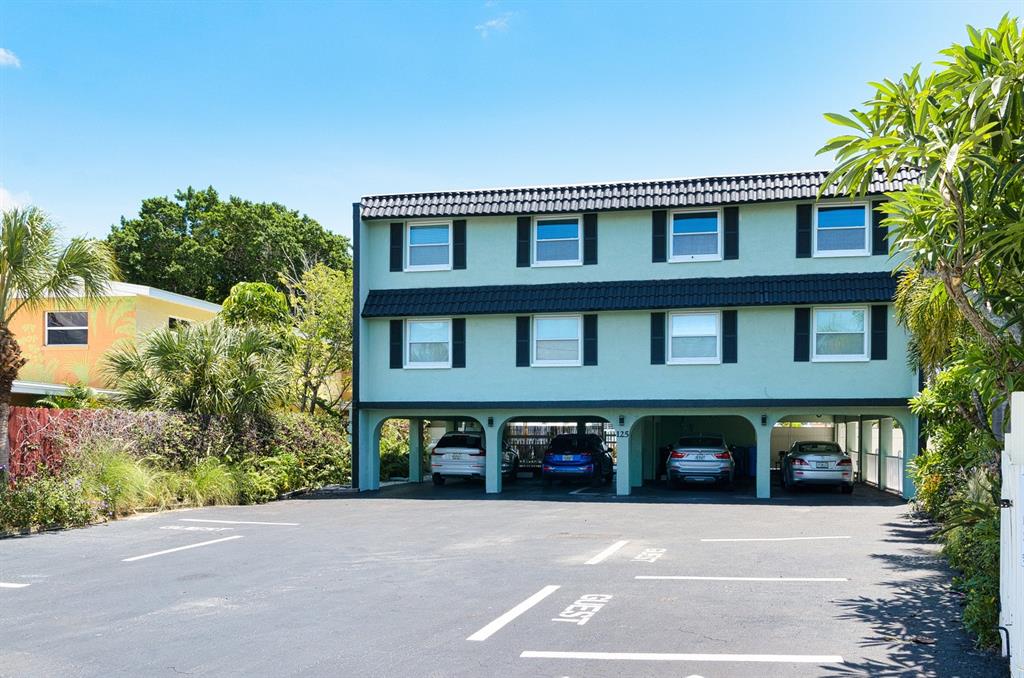 A three-story light green apartment building with covered parking on the ground level — 125 110TH AVENUE UNIT 1, TREASURE ISLAND, FL
