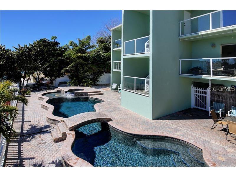 A multi-story building with balconies overlooks a two-level swimming pool with a stone bridge — 125 110TH AVENUE UNIT 1, TREASURE ISLAND, FL