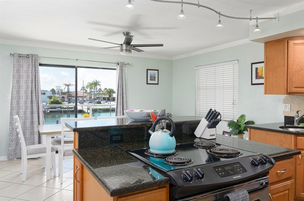 A kitchen with dark granite countertops, a light blue tea kettle, and a water view — 125 110TH AVENUE UNIT 1, TREASURE ISLAND, FL