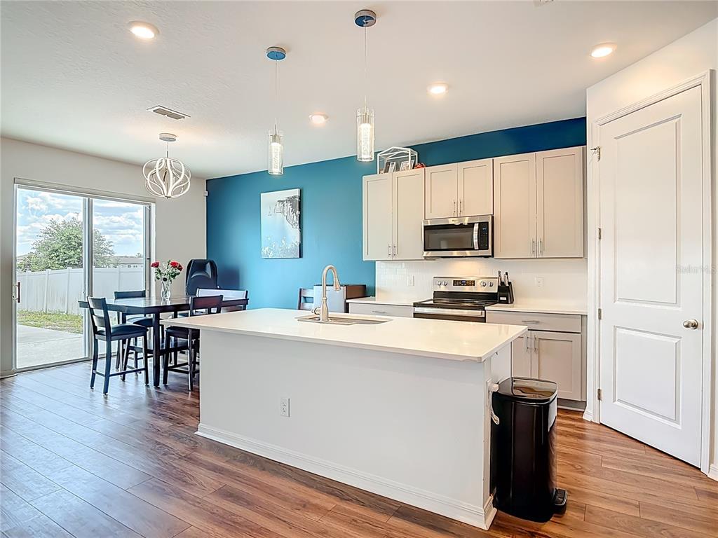 A kitchen with a white island, light-colored cabinets, and a blue accent wall — 1629 HILL PARK DRIVE, DELTONA, FL