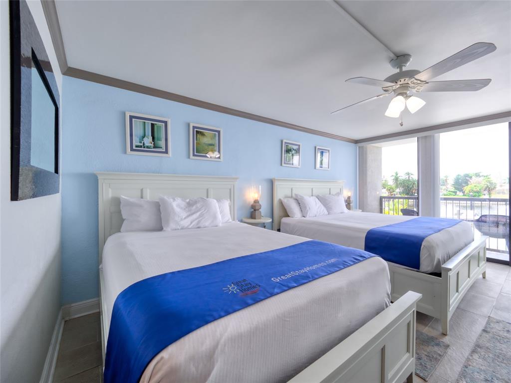 A bedroom features two beds with blue runners, light blue walls, and a ceiling fan — 7150 N TAMIAMI TRAIL UNIT N409, SARASOTA, FL