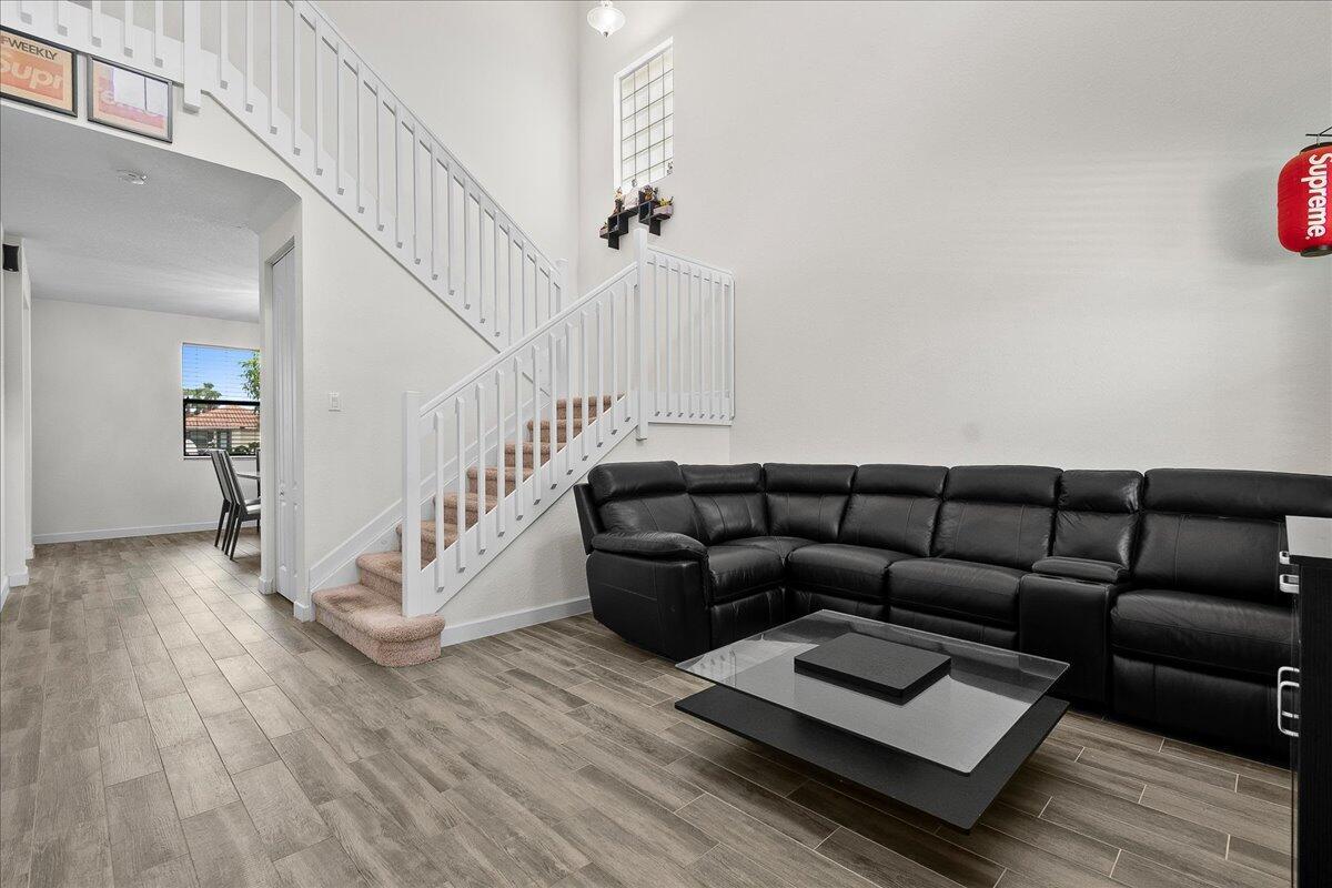 A living room features a black leather sectional, a glass coffee table, and a staircase — 6021 Night Heron Court, FL 33415, FL
