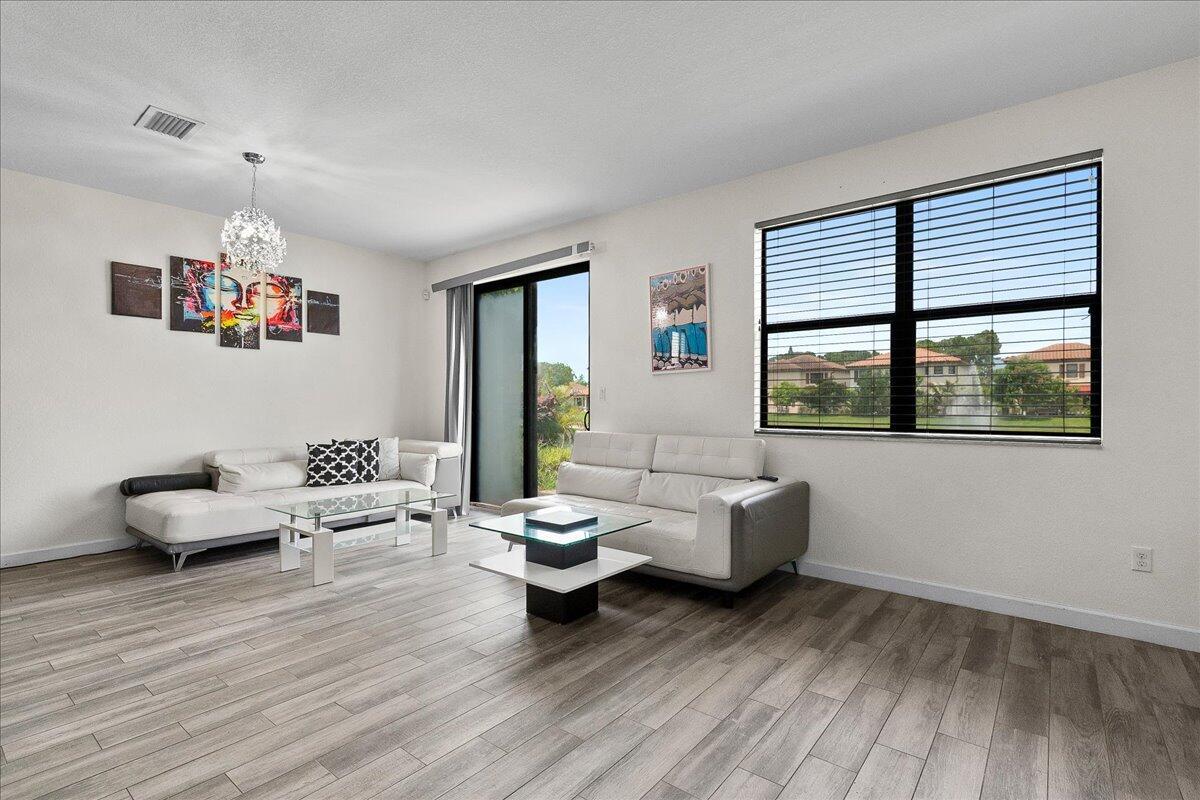 A living room with two white sofas, glass coffee tables, and a view of a fountain — 6021 Night Heron Court, FL 33415, FL