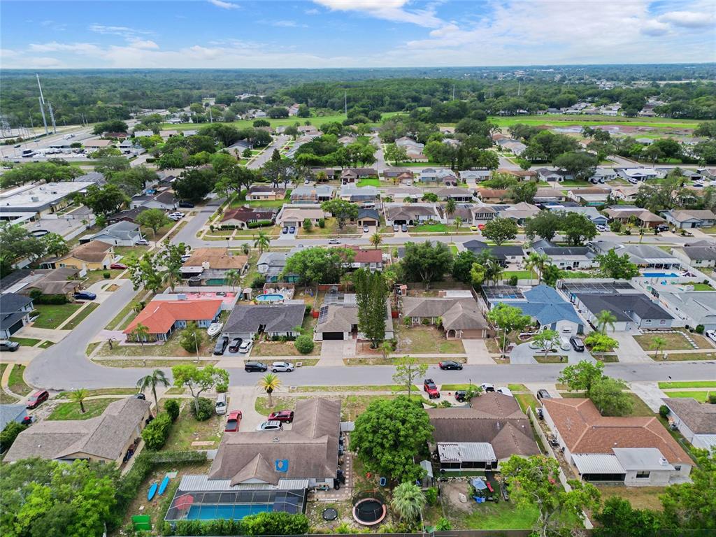 An aerial view shows a suburban neighborhood with single-family homes, paved streets, and green trees — 10951 PEPPERTREE LN, PORT RICHEY,, FL