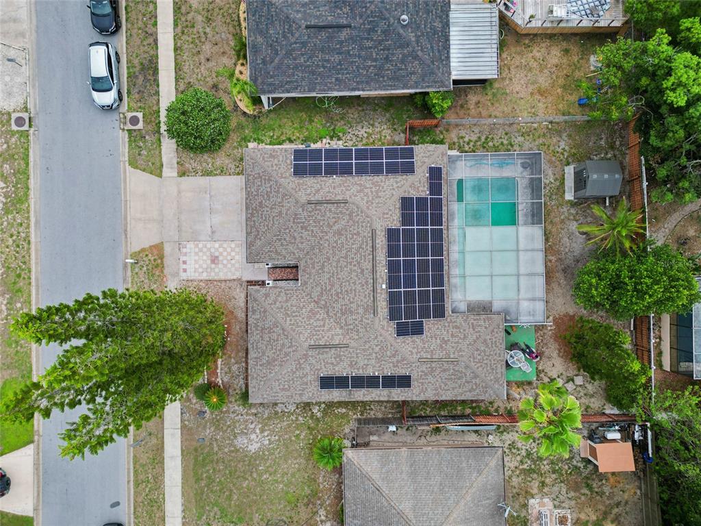 An aerial view shows a house with solar panels on the roof and a screened pool — 10951 PEPPERTREE LN, PORT RICHEY,, FL