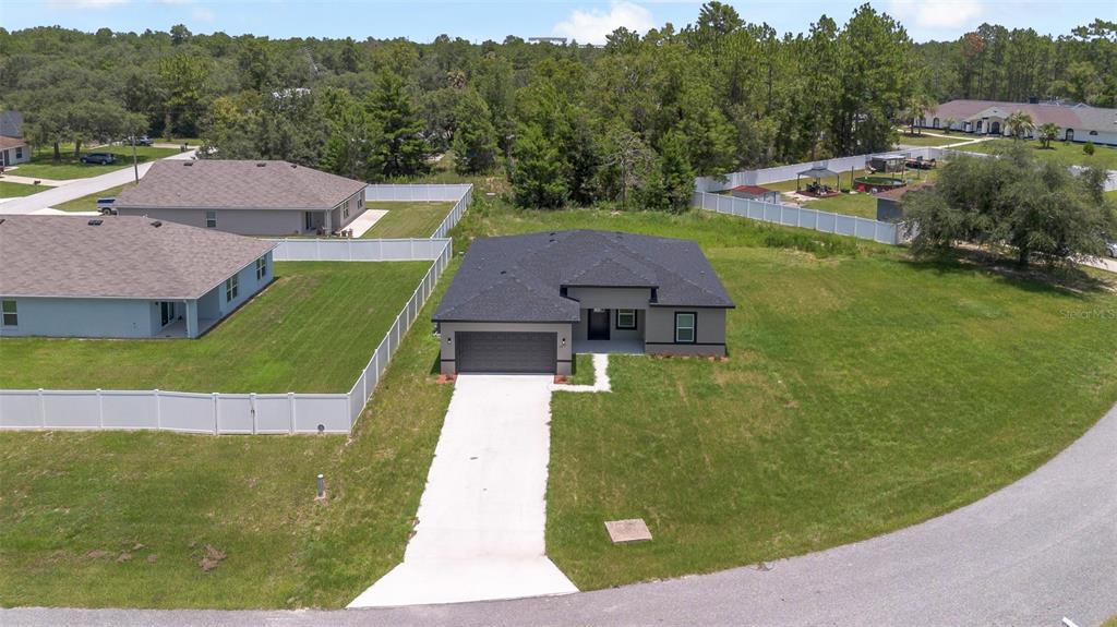 An aerial view shows a modern single-story house with a gray exterior and dark roof — 15690 SW 49TH AVENUE ROAD, OCALA, FL