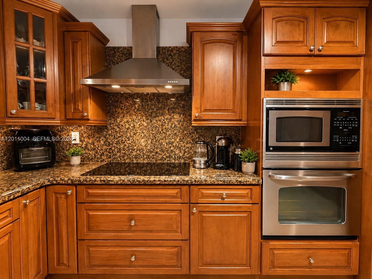 A kitchen features wood cabinets, granite countertops, a stainless steel range hood, and built-in appliances — 10290 SW 24th Ct, Miramar FL 33025, MIRAMAR, FL