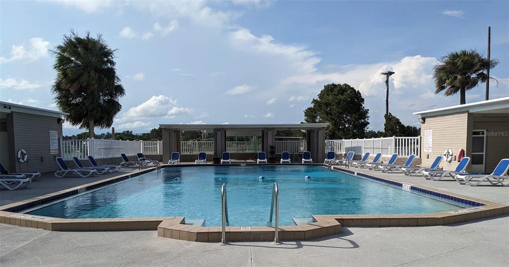 An outdoor swimming pool surrounded by lounge chairs and two small buildings under a blue sky — 4409 CLUB CIRCLE, LAKE WALES, FL