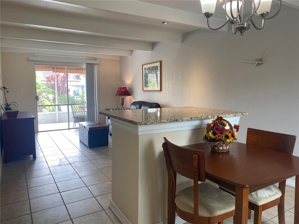 A dining area with a granite-topped breakfast bar overlooks a living room and patio — 4409 CLUB CIRCLE, LAKE WALES, FL
