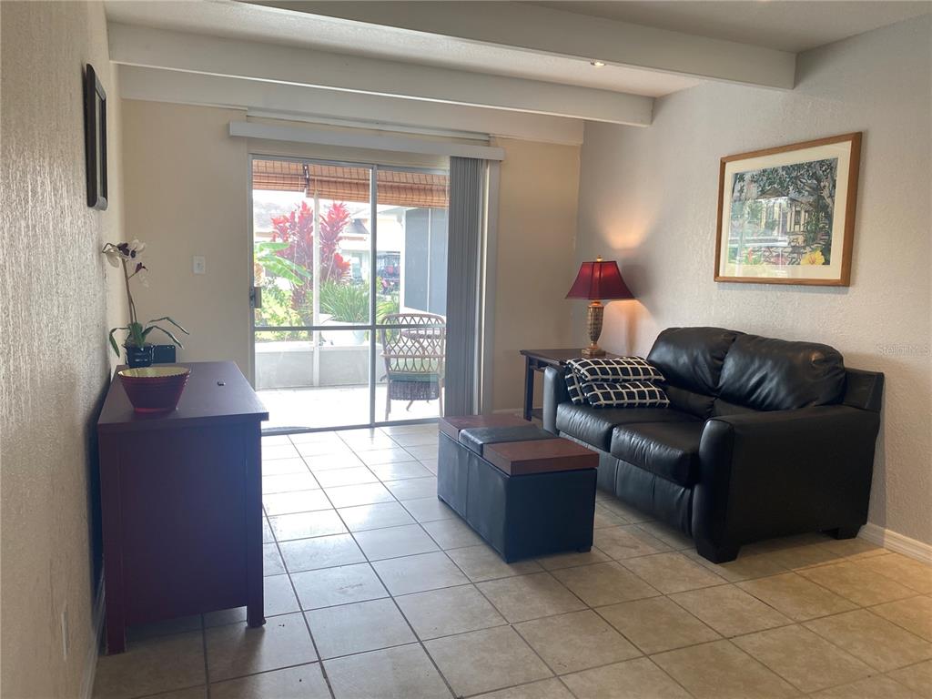 A living room features tile flooring, a black leather sofa, and a sliding glass door — 4409 CLUB CIRCLE, LAKE WALES, FL