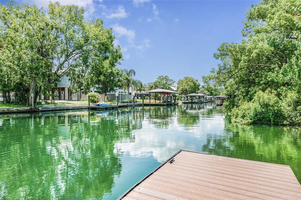 A wooden dock overlooks a calm canal lined with lush trees and private boat slips — 1201 SE PARADISE AVENUE, CRYSTAL RIVER, FL