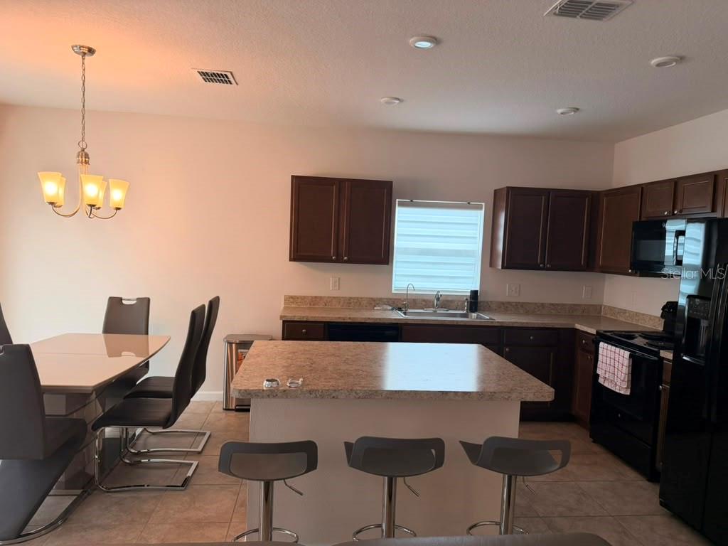 A kitchen with dark wood cabinets, a central island, and a dining area with chairs — 1052 KOBUK STREET, HAINES CITY, FL