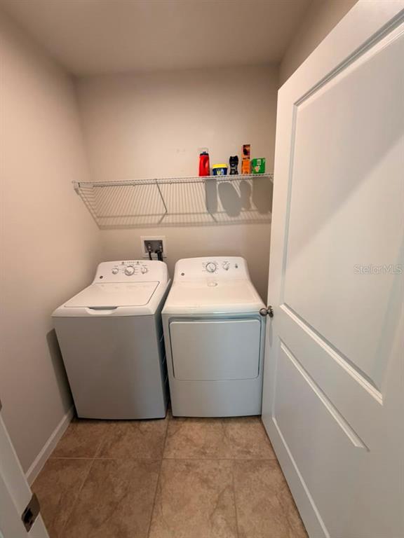 A laundry room features a white washer and dryer beneath a wire shelf — 1052 KOBUK STREET, HAINES CITY, FL
