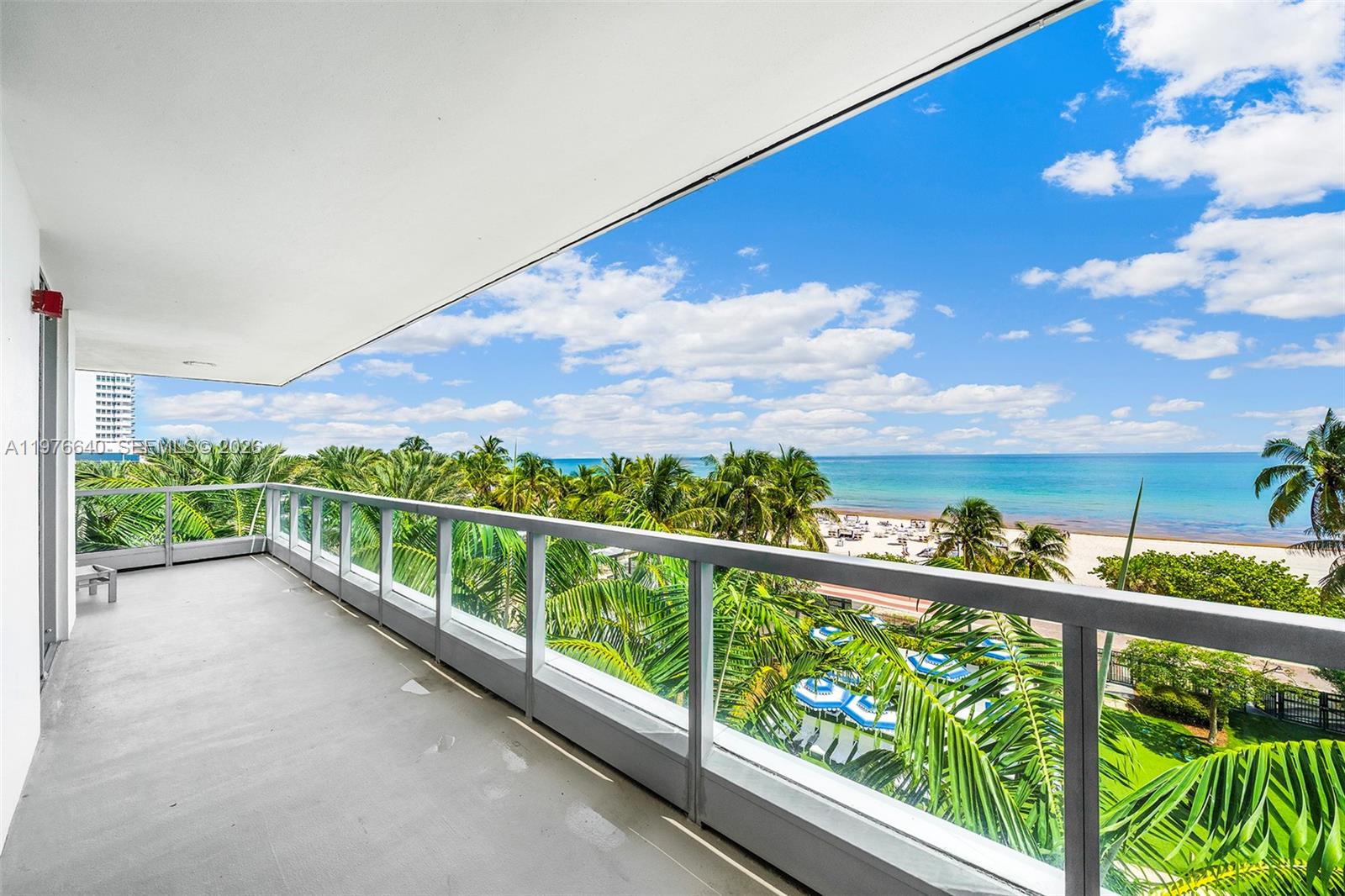 A balcony with a glass railing overlooks palm trees, a sandy beach, and the ocean — 4391 Collins Ave # 410, Miami Beach FL 33140, MIAMI BEACH, FL
