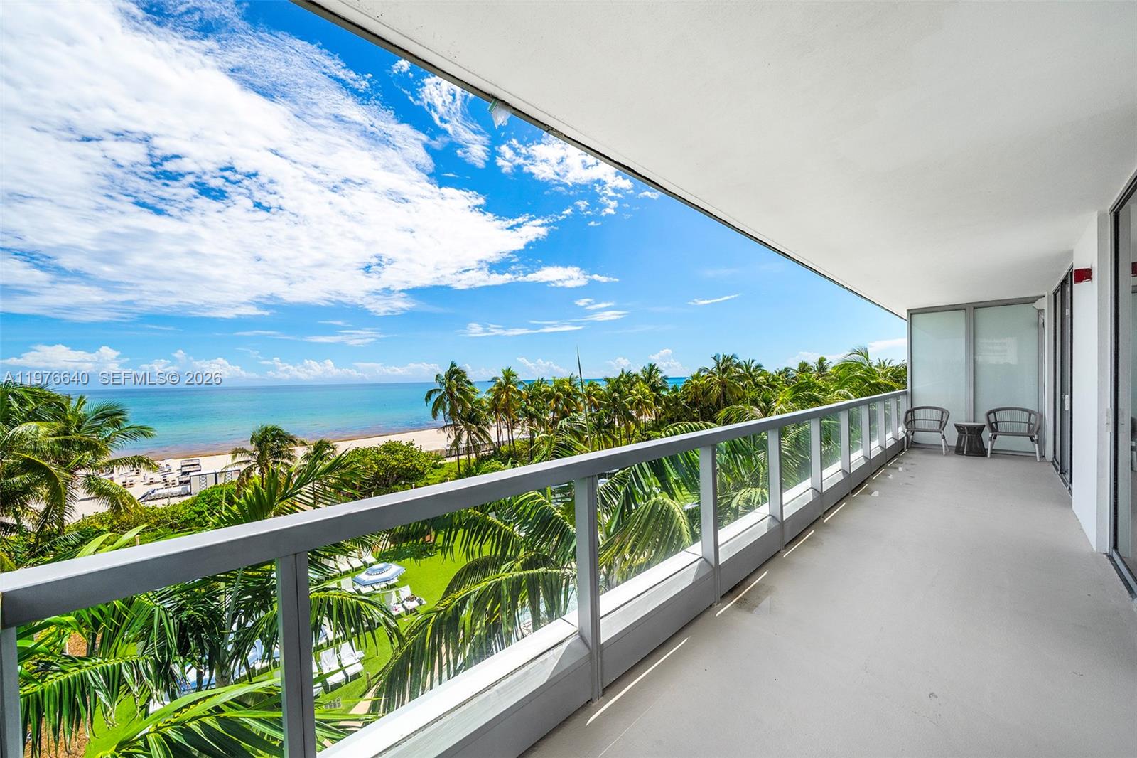 A balcony with a glass railing overlooks a beach, palm trees, and the ocean — 4391 Collins Ave # 410, Miami Beach FL 33140, MIAMI BEACH, FL
