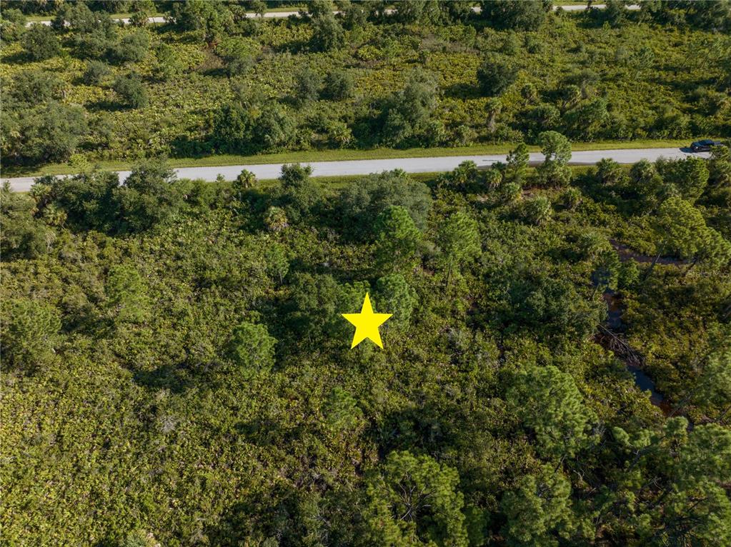 An aerial view shows a yellow star marking a wooded, undeveloped plot of land — 13211 CHIMINIELLO DRIVE, PORT CHARLOTTE, FL