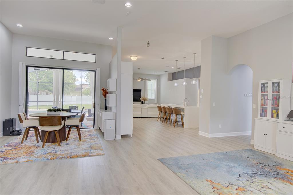 An open-concept living area features a dining space, kitchen island with barstools, and light flooring — 2407 FOLIAGE OAK TERRACE, OVIEDO, FL