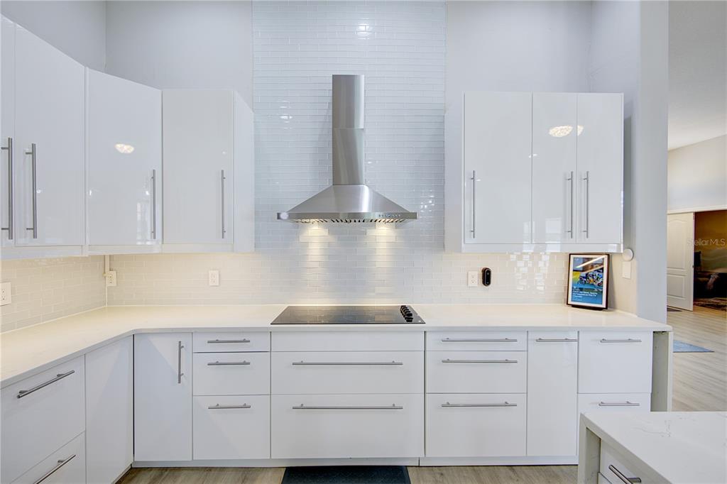 A modern kitchen features white glossy cabinets, a stainless steel range hood, and white subway tile — 2407 FOLIAGE OAK TERRACE, OVIEDO, FL