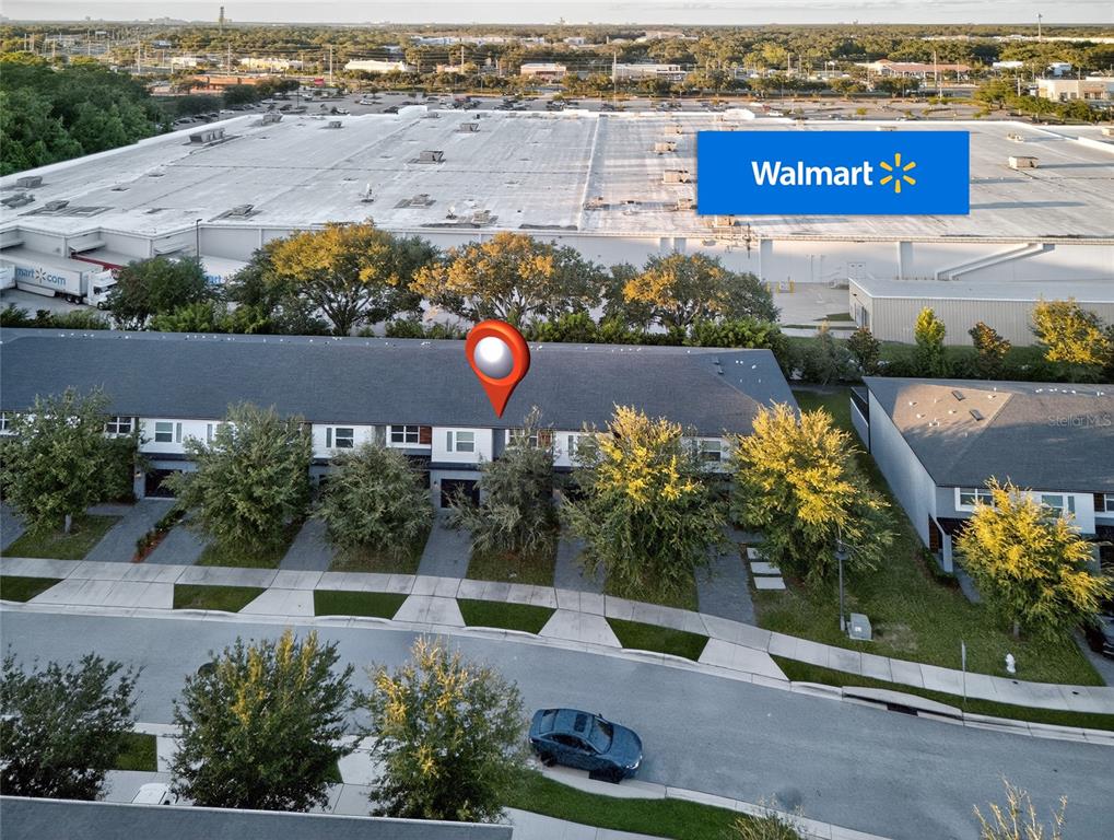 An aerial view shows a row of townhouses located directly behind a large Walmart store — 4433 LE REVE COURT, KISSIMMEE, FL