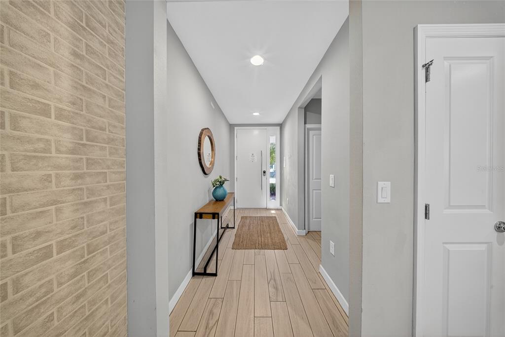 A bright entryway features a wood-look tile floor, a console table, and a white door — 4433 LE REVE COURT, KISSIMMEE, FL