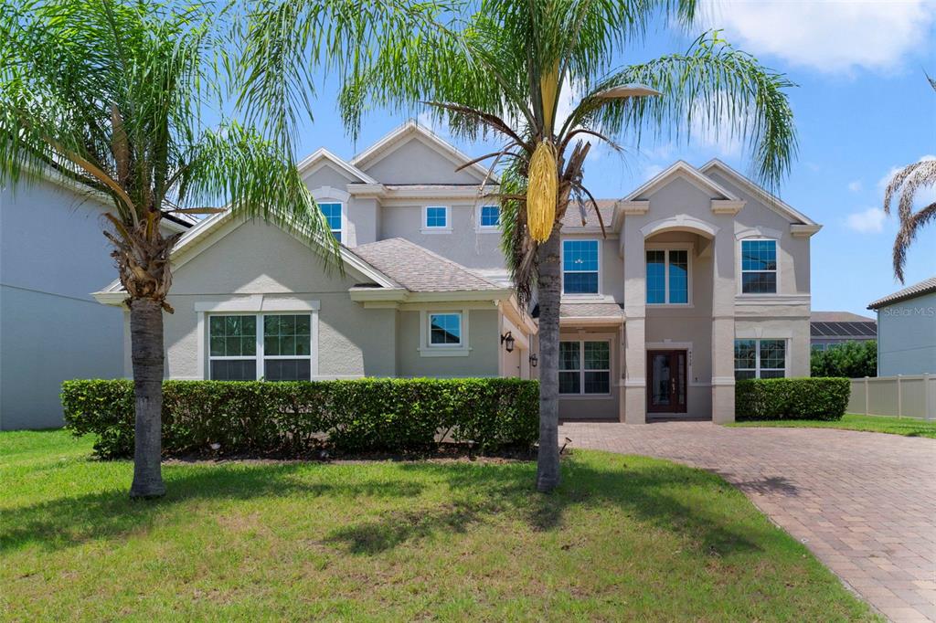 A two-story suburban house with a paved driveway, palm trees, and a manicured hedge — 4958 CYPRESS HAMMOCK DRIVE, ST CLOUD, FL