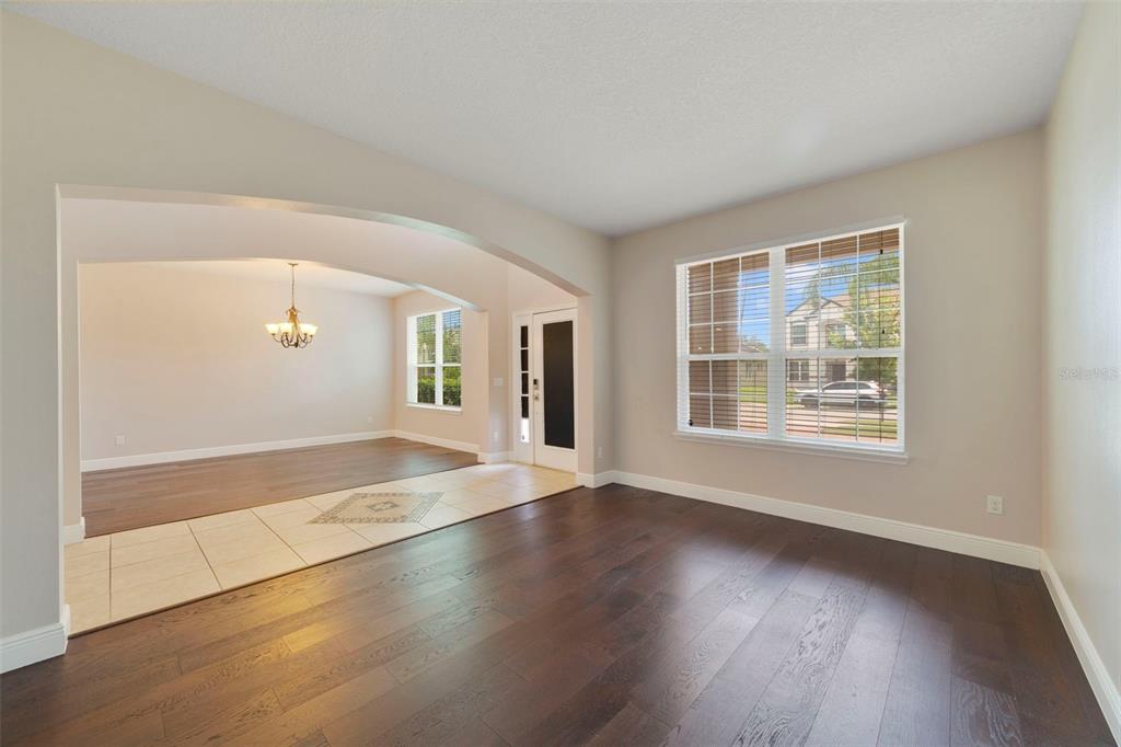 A living room with dark wood floors and a tiled entryway leading to a dining area — 4958 CYPRESS HAMMOCK DRIVE, ST CLOUD, FL