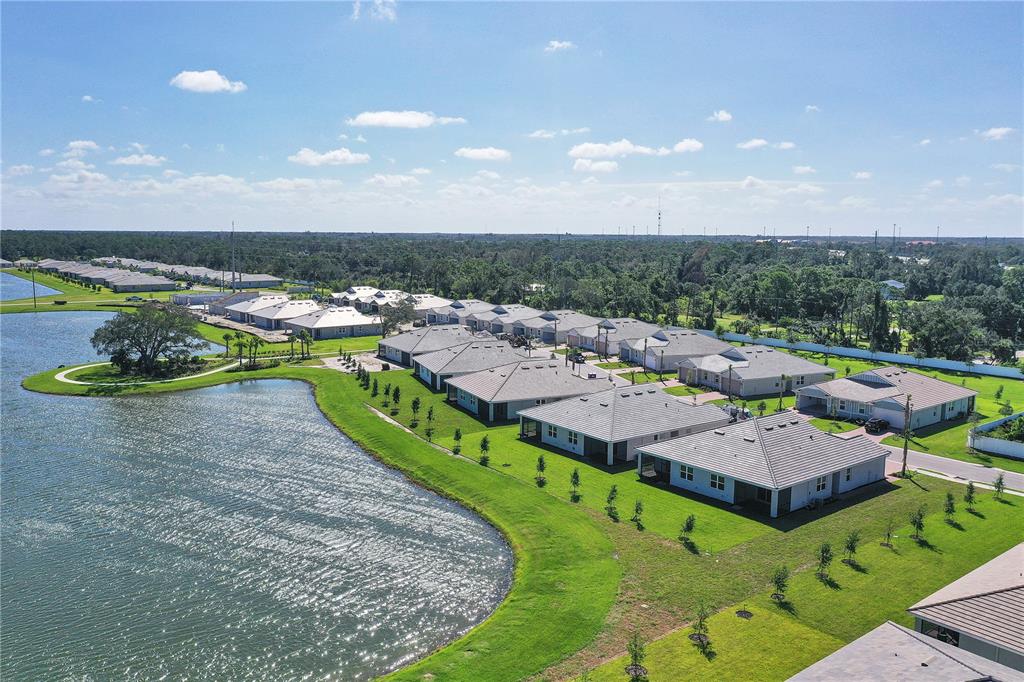 An aerial view shows a suburban neighborhood with houses situated along a large lake — 305 IBIZA LOOP, VENICE, FL