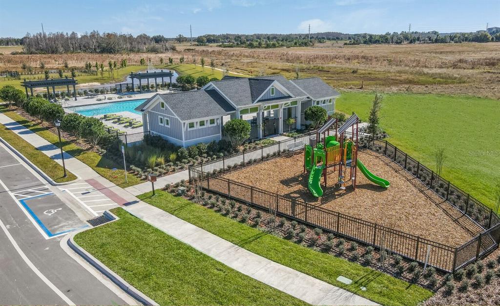 An aerial view of a community clubhouse with a swimming pool and a fenced playground — 28789 SEEDLING STREET, WESLEY CHAPEL, FL