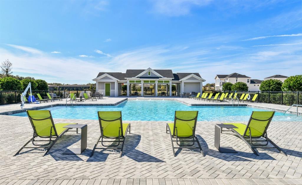 A swimming pool with lounge chairs on a paved deck in front of a clubhouse — 28789 SEEDLING STREET, WESLEY CHAPEL, FL