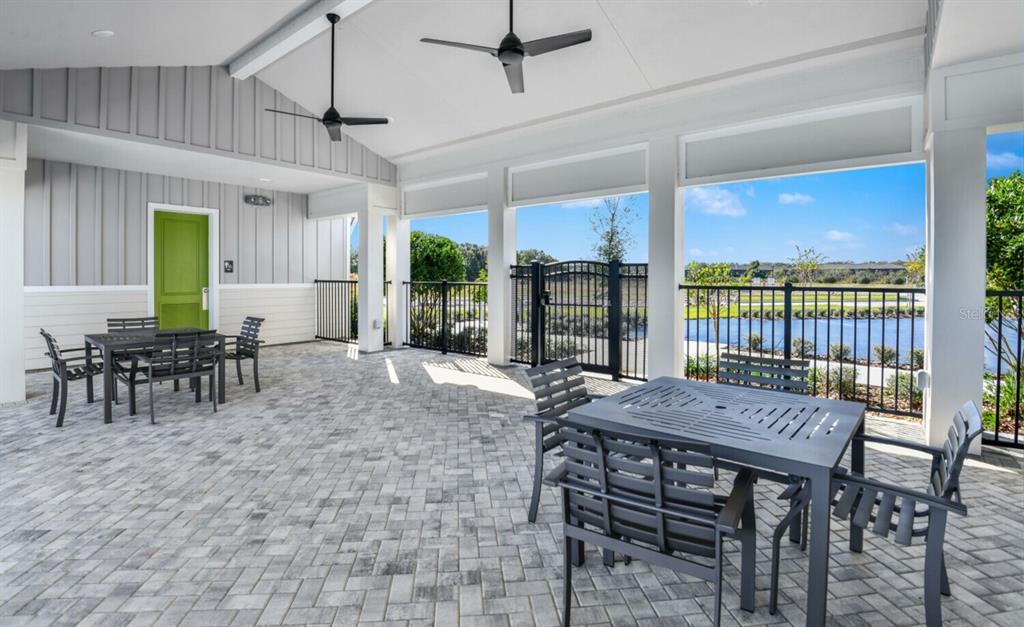 A covered outdoor patio features two dining sets, ceiling fans, and a view of water — 28789 SEEDLING STREET, WESLEY CHAPEL, FL