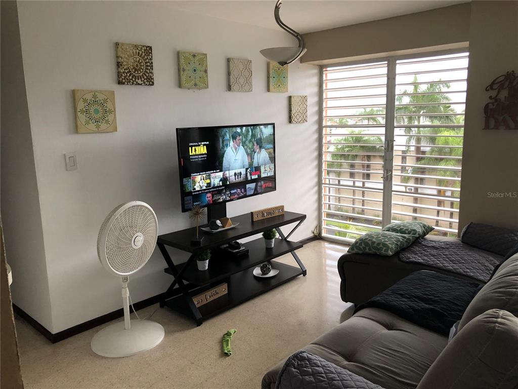 A living room features a television on a black stand, a sofa, and a floor fan — 274 CALLE URUGUAY UNIT 202, SAN JUAN, PR