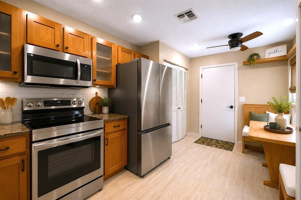 A kitchen features wood cabinets, stainless steel appliances, a dining nook, and light-colored flooring — 641 MAPLE OAK CIRCLE UNIT 101, ALTAMONTE SPRINGS, FL