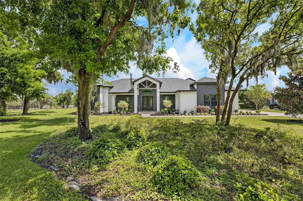 A modern single-story house with a dark gray roof and white exterior walls — 16410 ALDERMAN TURNER ROAD, WIMAUMA, FL