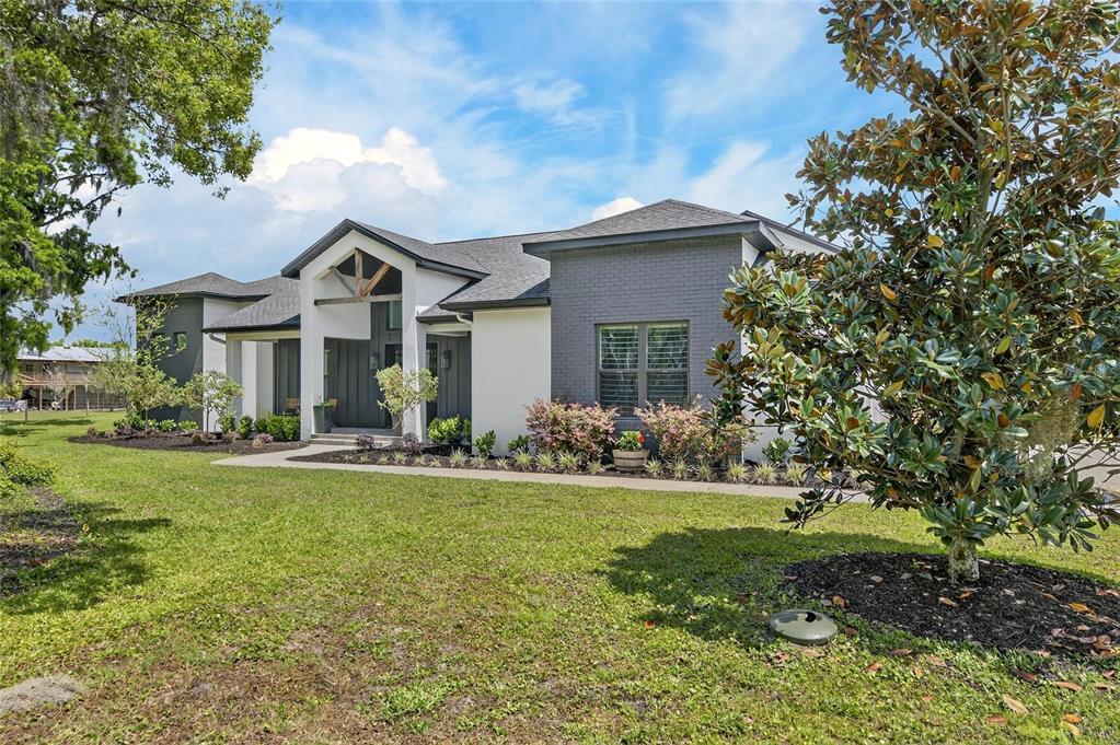 A modern single-story house features a white and gray exterior with a gabled entryway — 16410 ALDERMAN TURNER ROAD, WIMAUMA, FL