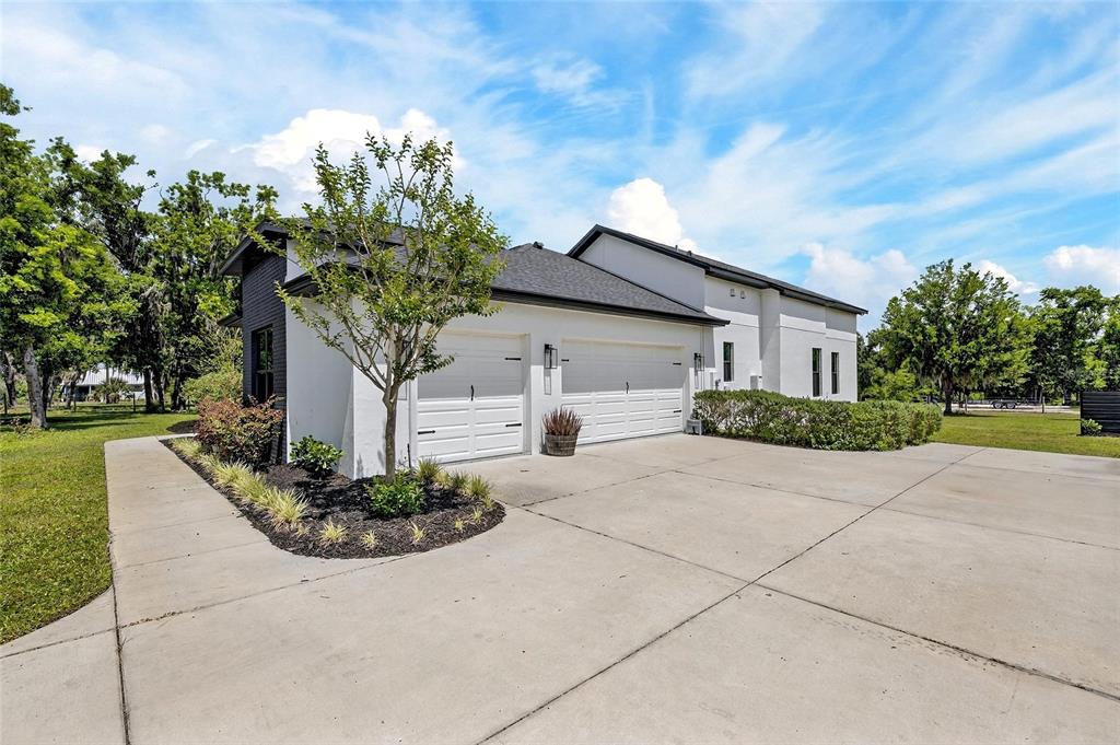A white house with a two-car garage and a concrete driveway under a blue sky — 16410 ALDERMAN TURNER ROAD, WIMAUMA, FL