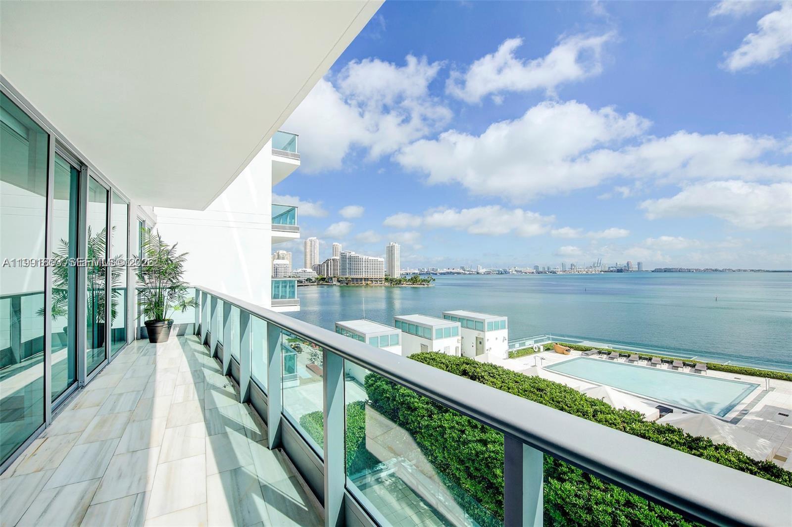 A balcony with glass railings overlooks a swimming pool and a bay with city views — 1331 Brickell Bay Dr # 903, Miami FL 33131, MIAMI, FL