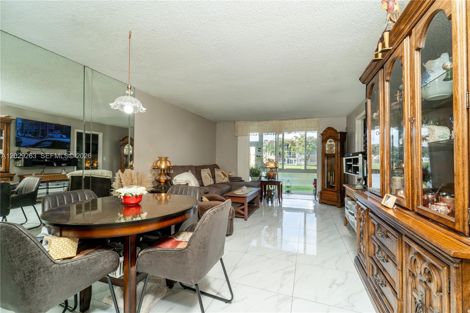 A living and dining area features white tile floors, a mirrored wall, and lake views — 2811 N Pine Island Rd # 102, Sunrise FL 33322, SUNRISE, FL