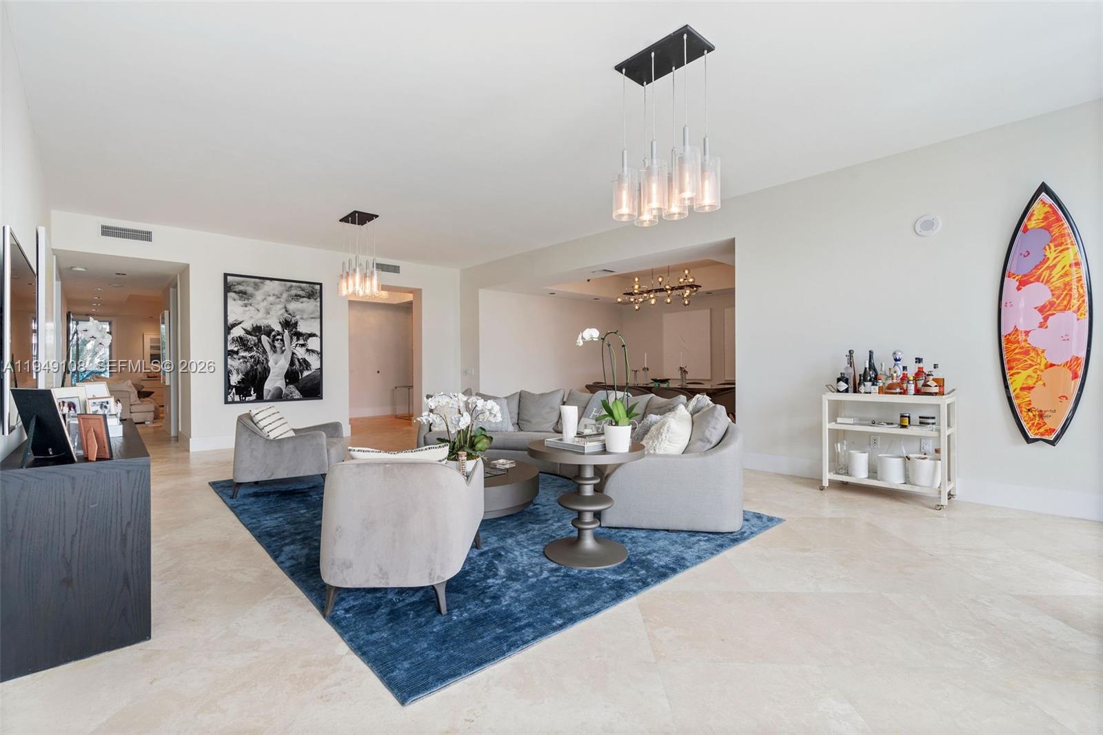 A living room features a blue area rug, gray sectional sofa, and a surfboard decoration — 5959 Collins Ave # 606, Miami Beach FL 33140, MIAMI BEACH, FL