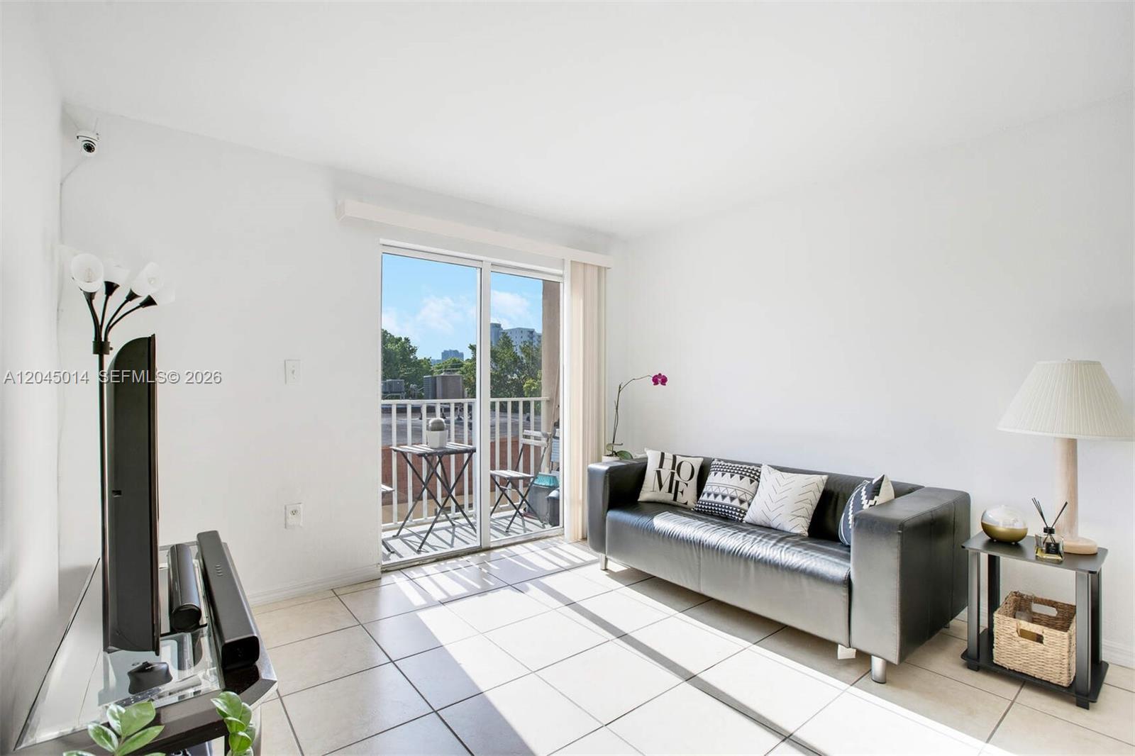 A living room features white walls, tile flooring, a black sofa, and a sliding glass door — 1349 SW 3rd St # 7, Miami FL 33135, MIAMI, FL