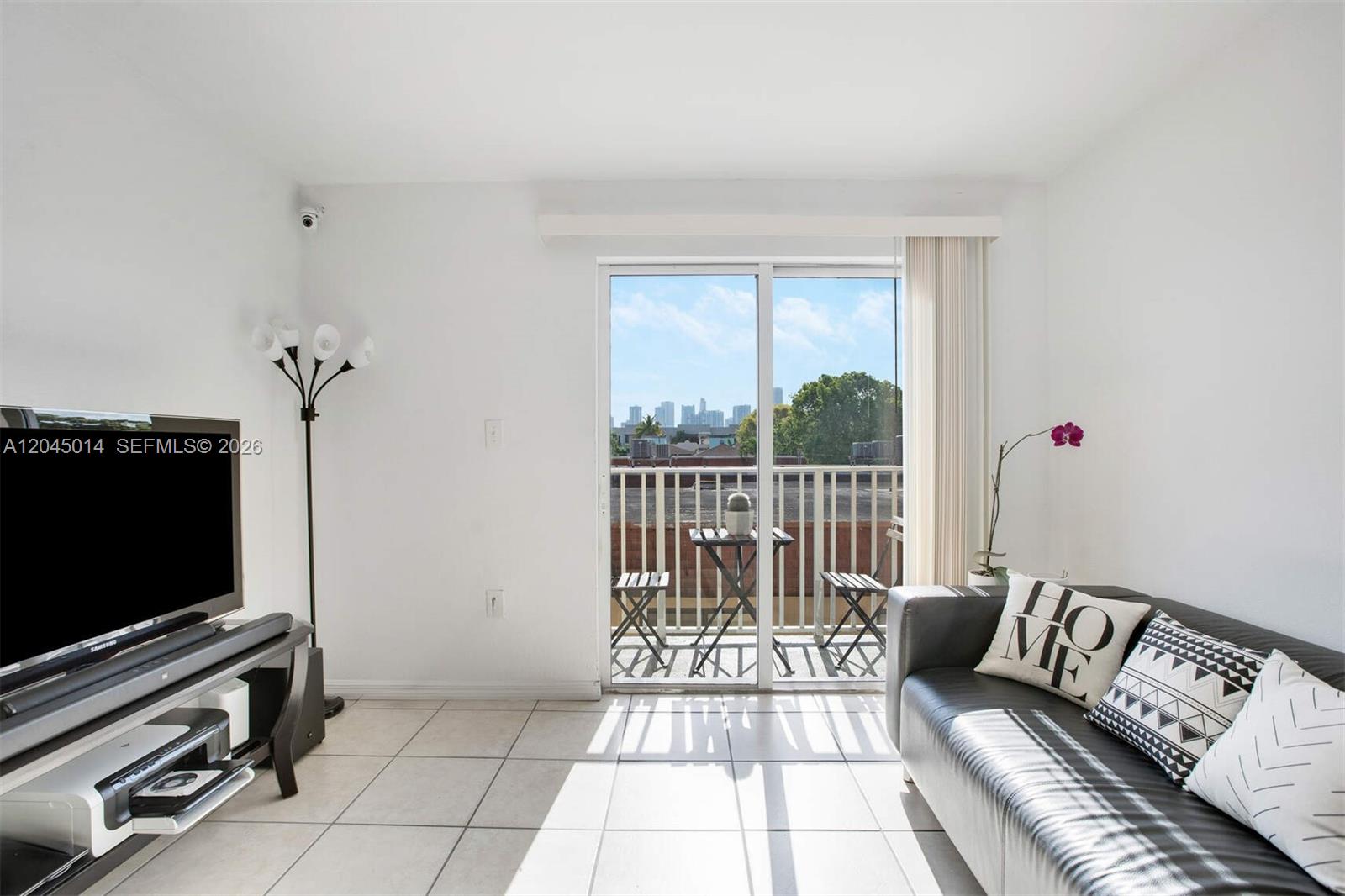 A living room features white tile floors, a black sofa, and a balcony with city views — 1349 SW 3rd St # 7, Miami FL 33135, MIAMI, FL