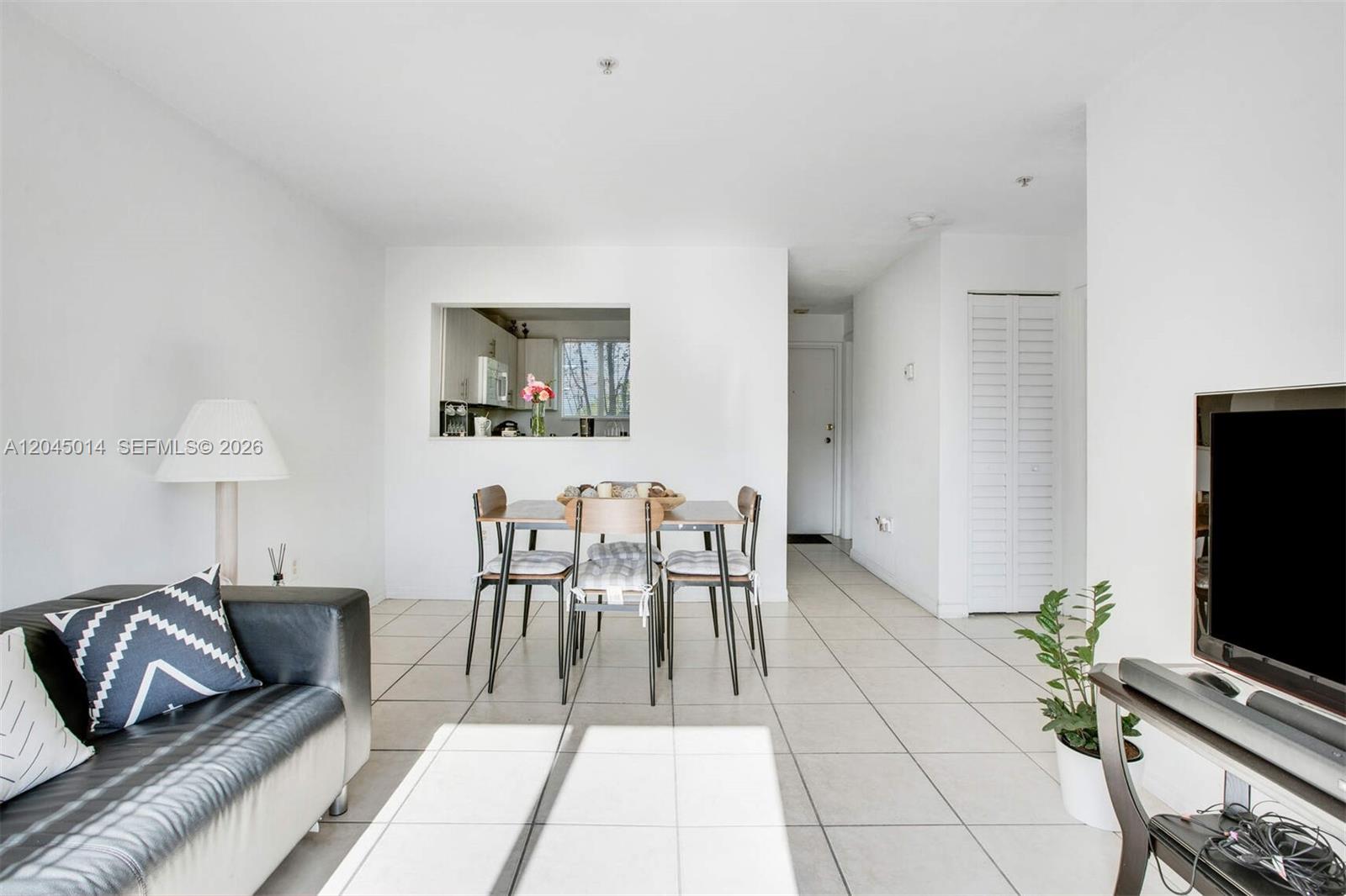A living and dining area features white walls, tile flooring, and a kitchen pass-through window — 1349 SW 3rd St # 7, Miami FL 33135, MIAMI, FL