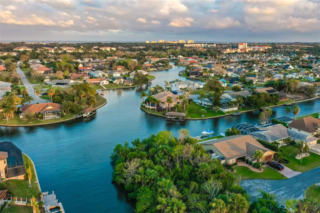 An aerial view of a waterfront residential neighborhood with canals, houses, and palm trees — 44 CLOVERDALE COURT N, PALM COAST, FL