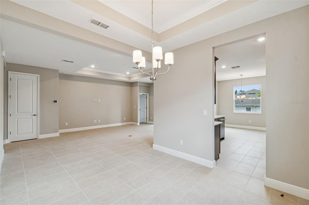 An open-concept dining area with tile flooring, a chandelier, and a view into the kitchen — 19474 LILY POND COURT, BROOKSVILLE, FL