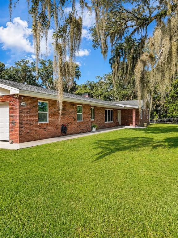 A single-story brick house with a gray roof sits on a large, grassy lawn — 1221 SW SKATES STREET, ARCADIA, FL