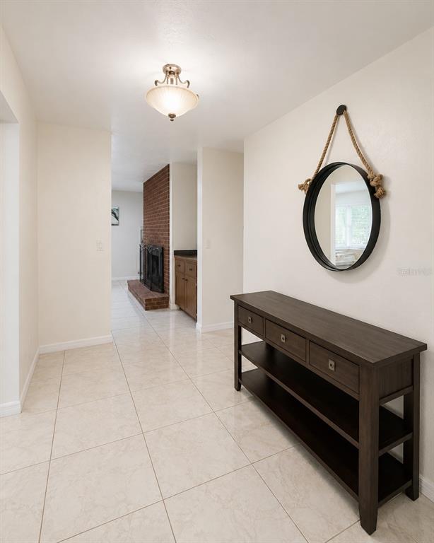 A tiled entryway features a dark wood console table, a round rope mirror, and a fireplace — 1221 SW SKATES STREET, ARCADIA, FL