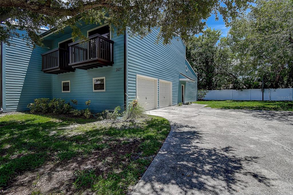 A two-story blue house with a balcony, two garage doors, and a concrete driveway — 6334 92ND PLACE N UNIT 2401, PINELLAS PARK, FL