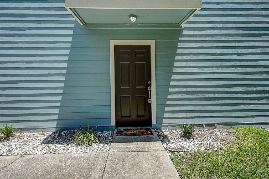 A dark brown front door is centered on a light blue horizontal-sided exterior wall — 6334 92ND PLACE N UNIT 2401, PINELLAS PARK, FL
