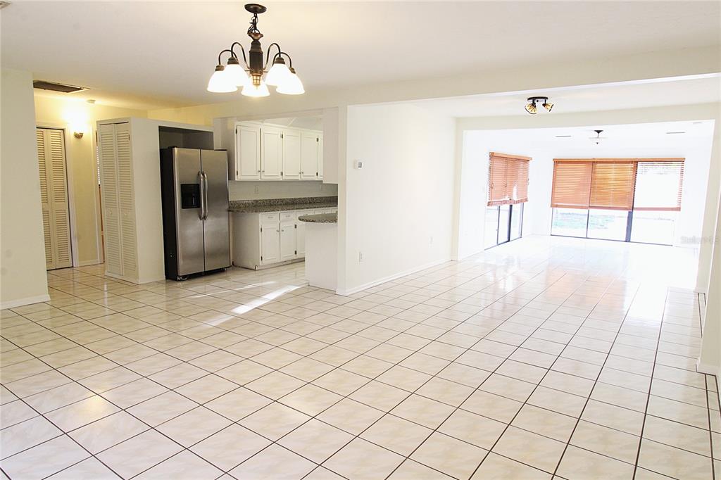 A bright, open-concept living and kitchen area features white tile flooring and white cabinetry — 2516 E MILMAR DRIVE, SARASOTA, FL